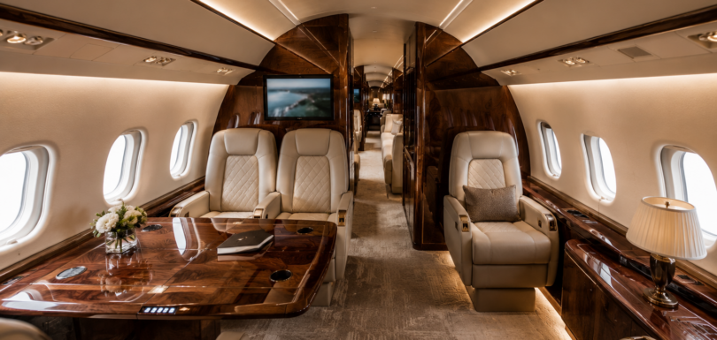 Custom luxury private jet cabin with cream leather seats, wood veneer panels and ambient lighting after VIP interior refurbishment