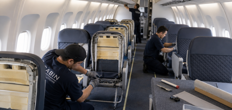 Aviation technicians refurbishing commercial aircraft cabin seats and sidewall panels inside a certified repair station